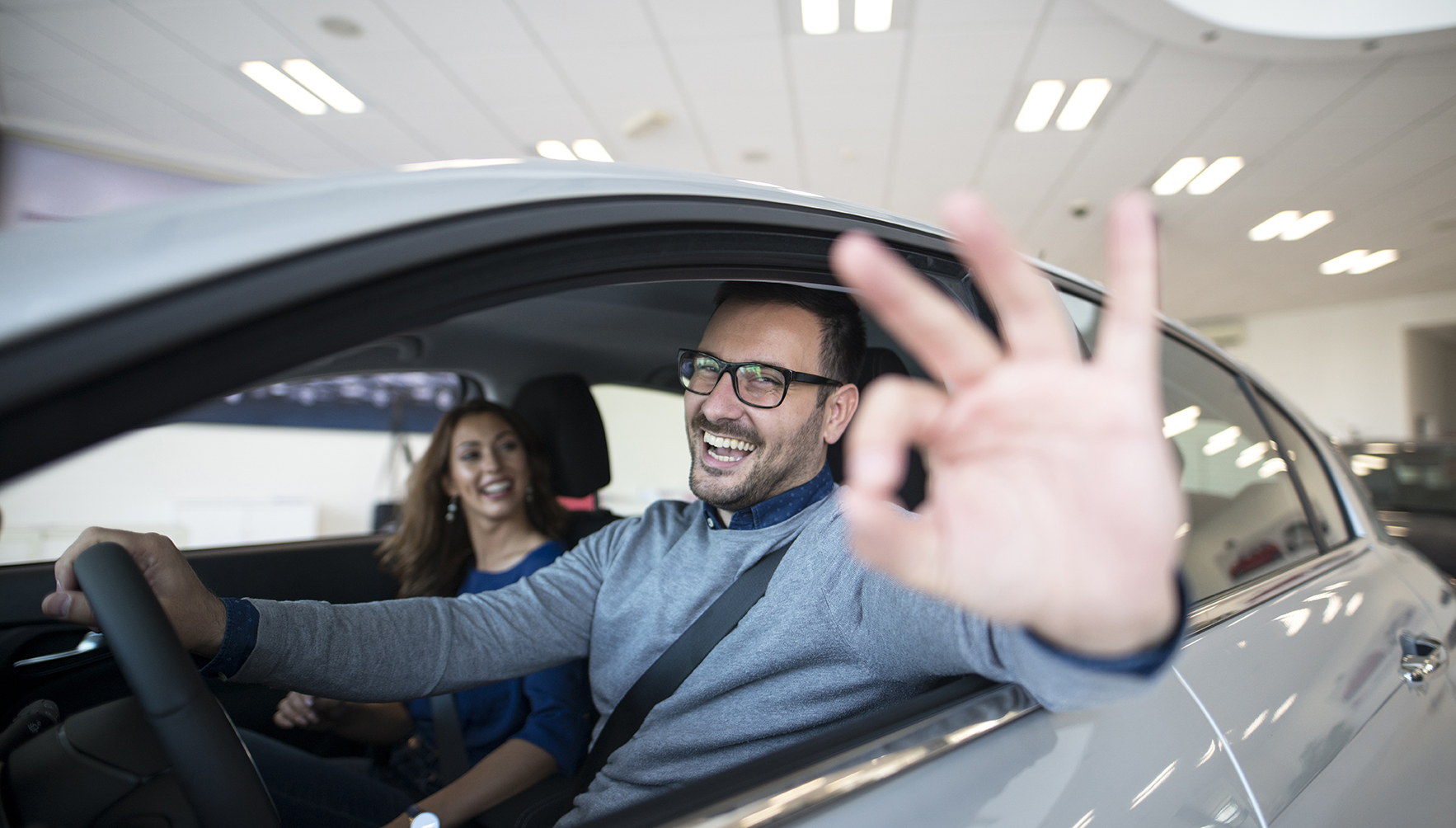 Happy customer buying new car at dealership.